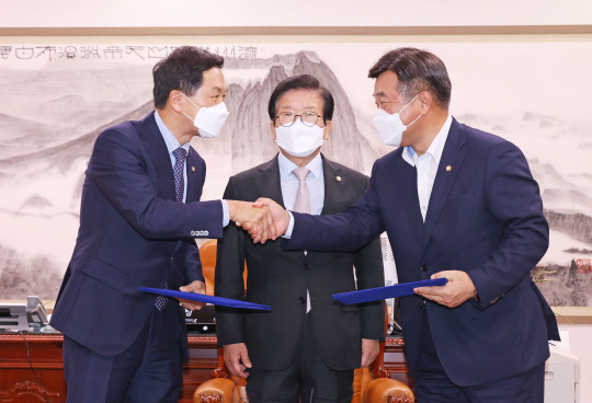 윤호중(오른쪽) 민주당 원내대표와 김기현(왼쪽) 국민의힘 원내대표가 지난달 31일 국회 의장실에서 언론중재법 개정안을 위한 협의체 구성과 9월 27일 본회의 상정 등을 담은 합의문을 교환하고 있다. 가운데는 박병석 국회의장. 연합뉴스